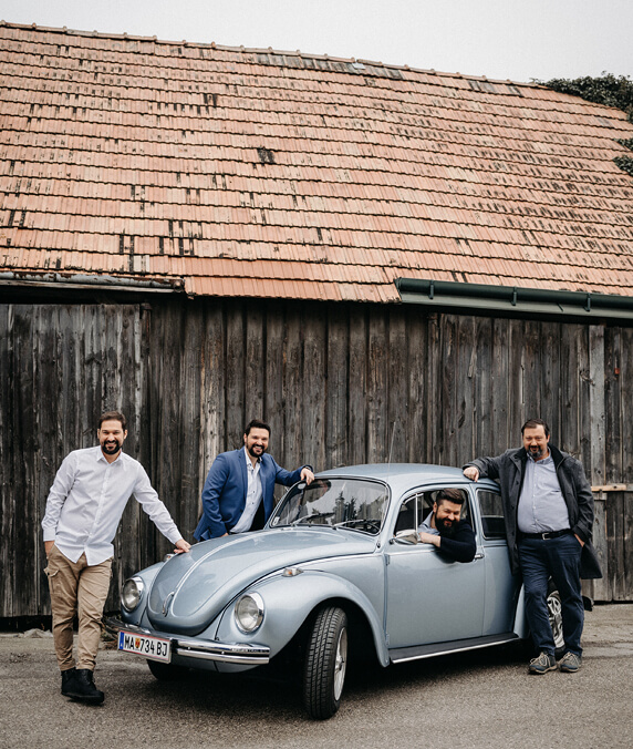 Anton, Michael, Klemens und Lukas stehen um einen hellblauen VW Käfer