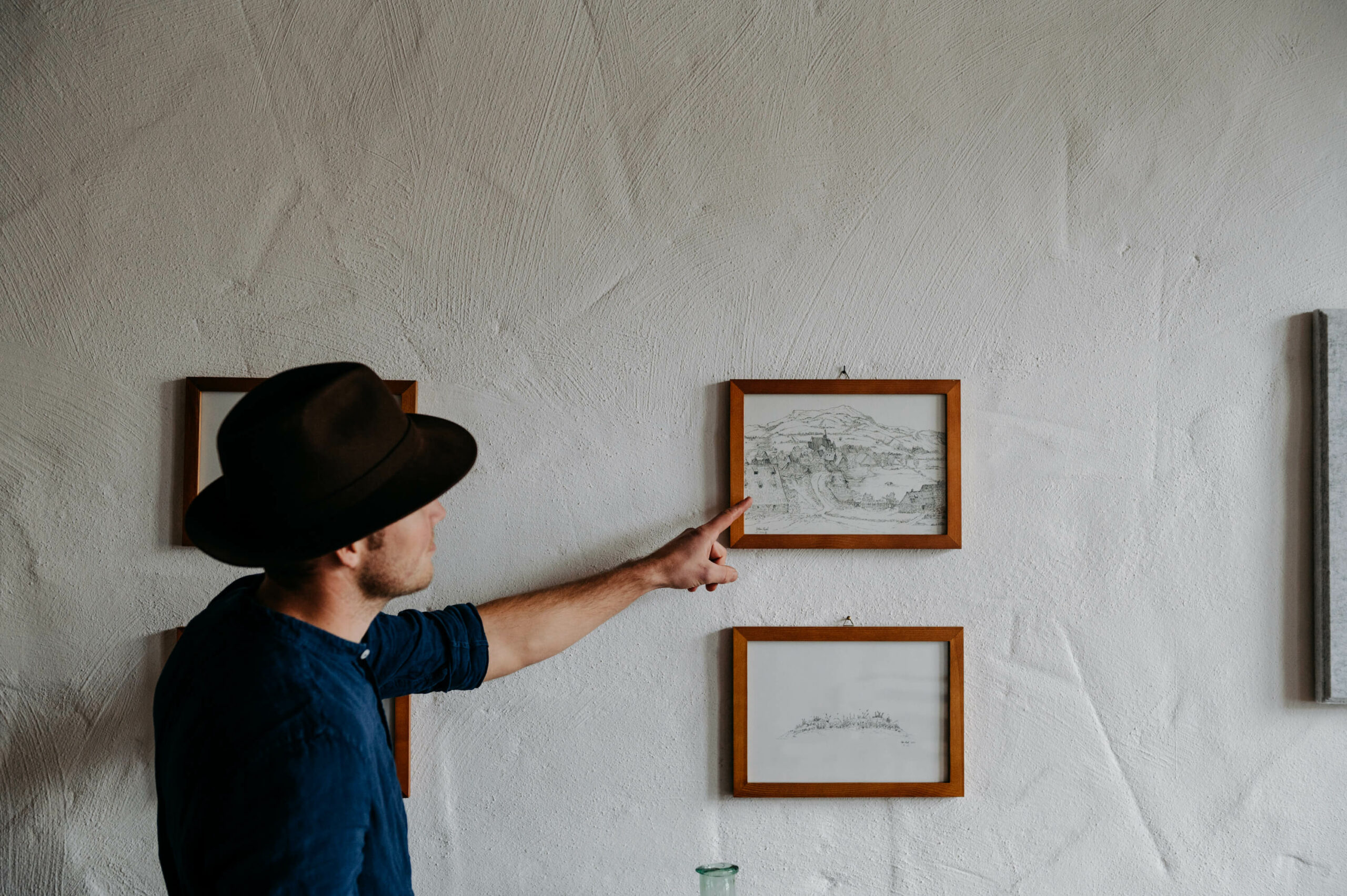 Herr Lassl zeigt auf ein Handgezeichnetes Bild in einem Holzrahmen das an der Wand hängt