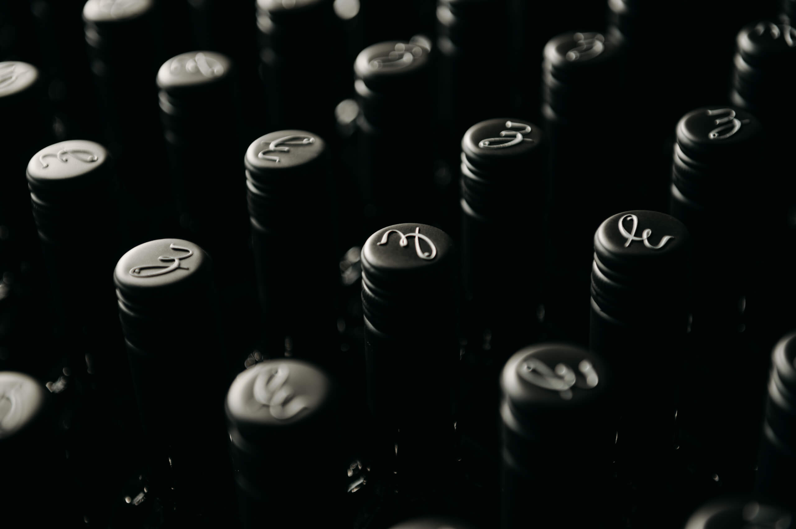 Schwarze Weinkapseln in einer Reihe mit einem weißen Buchstaben darauf