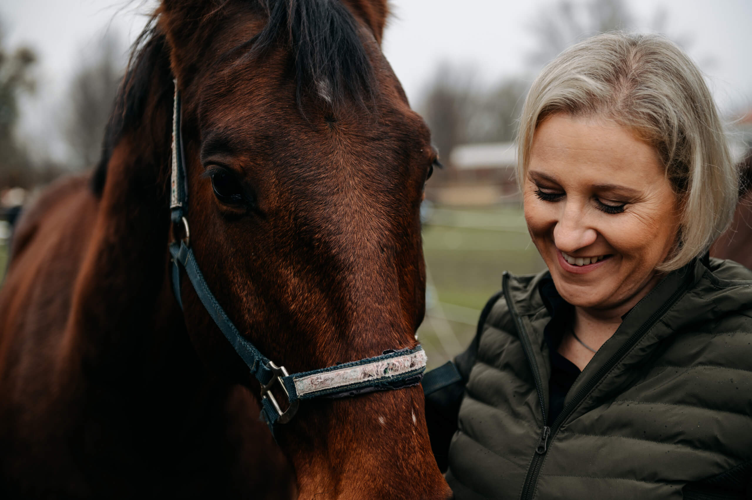 Anna Maria lächelt ein braunen Pferd an