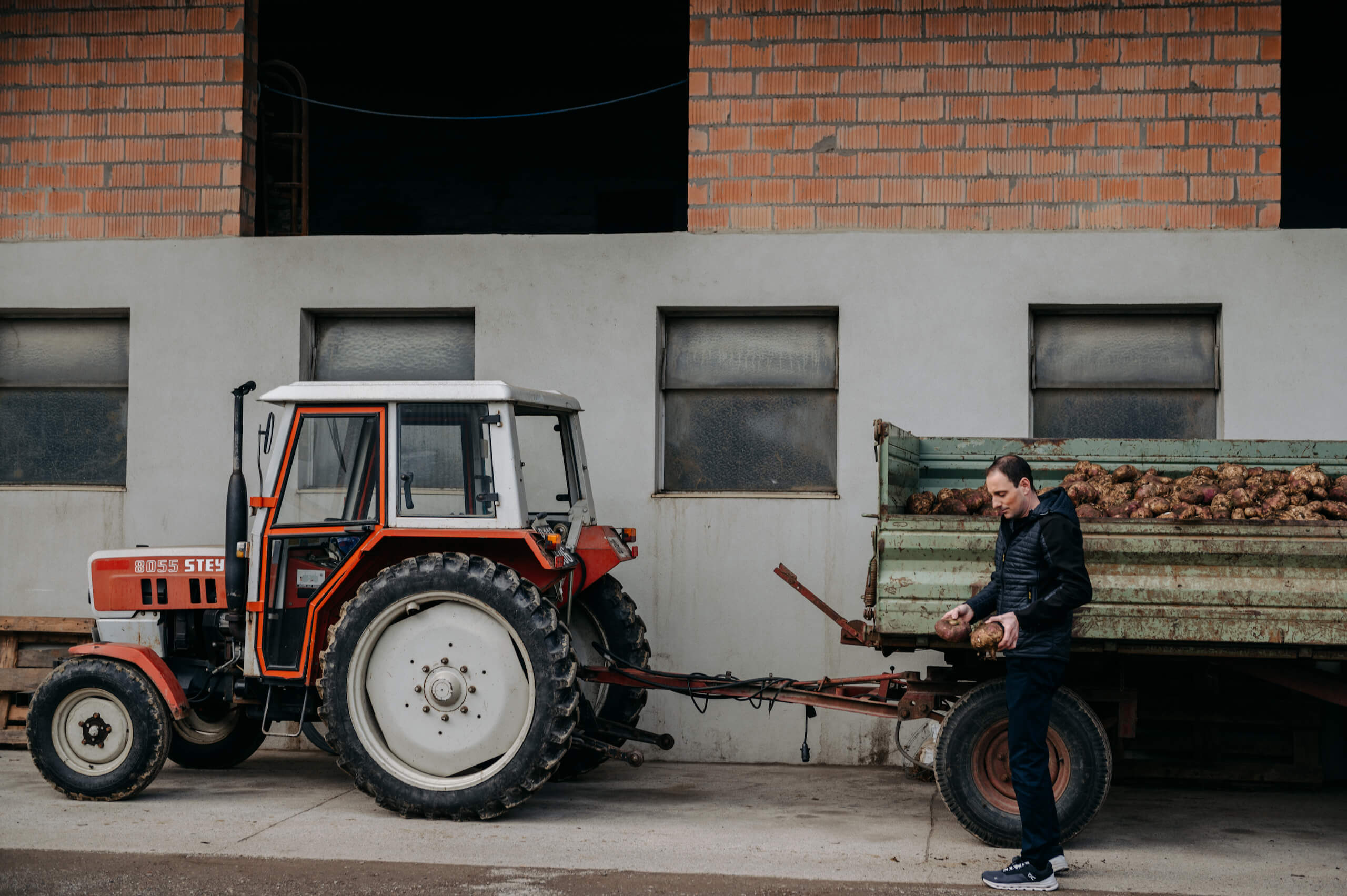 Herr Steiger steht vor einem roten Traktor mit einem grünen Anhänger