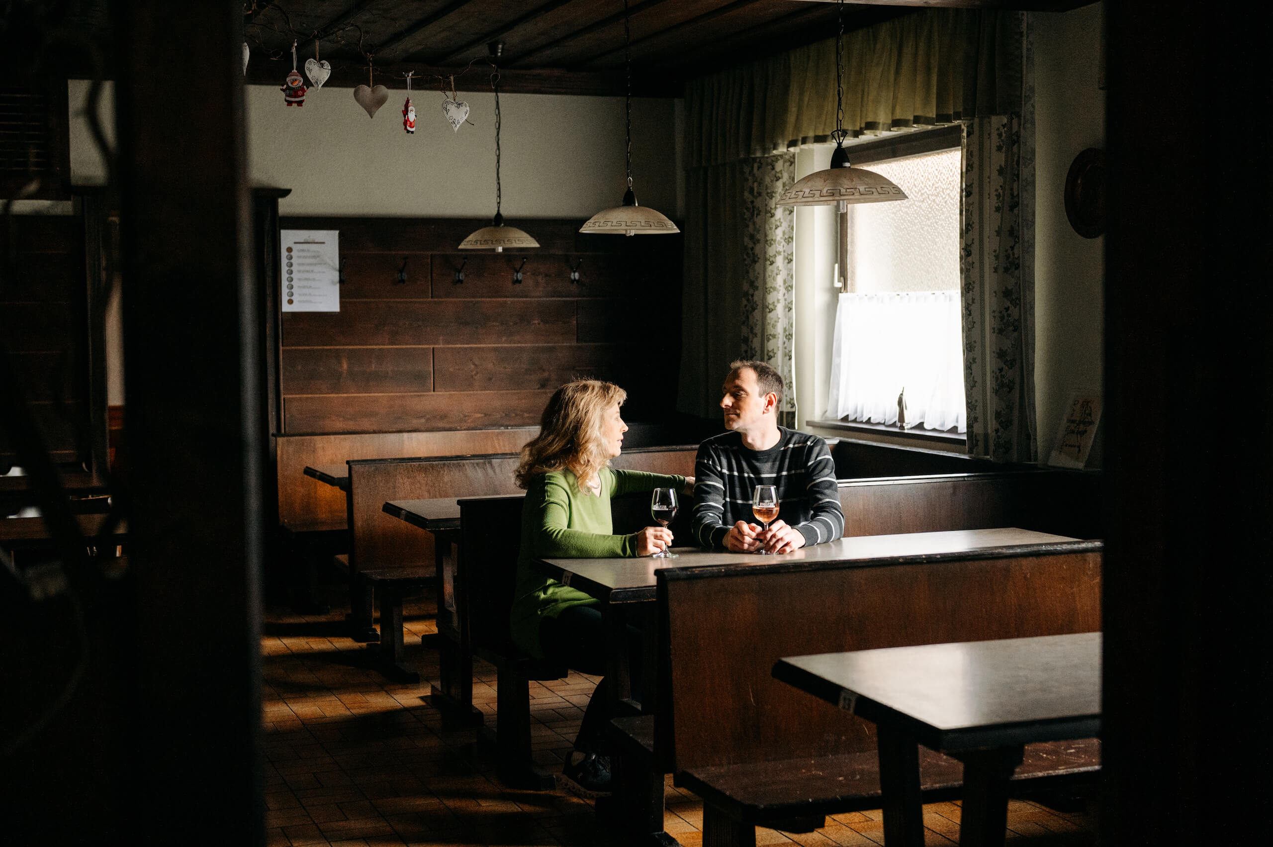 Herr und Frau Steiger sitzen im Heurigen an einem Tisch und trinken Rosé Wein